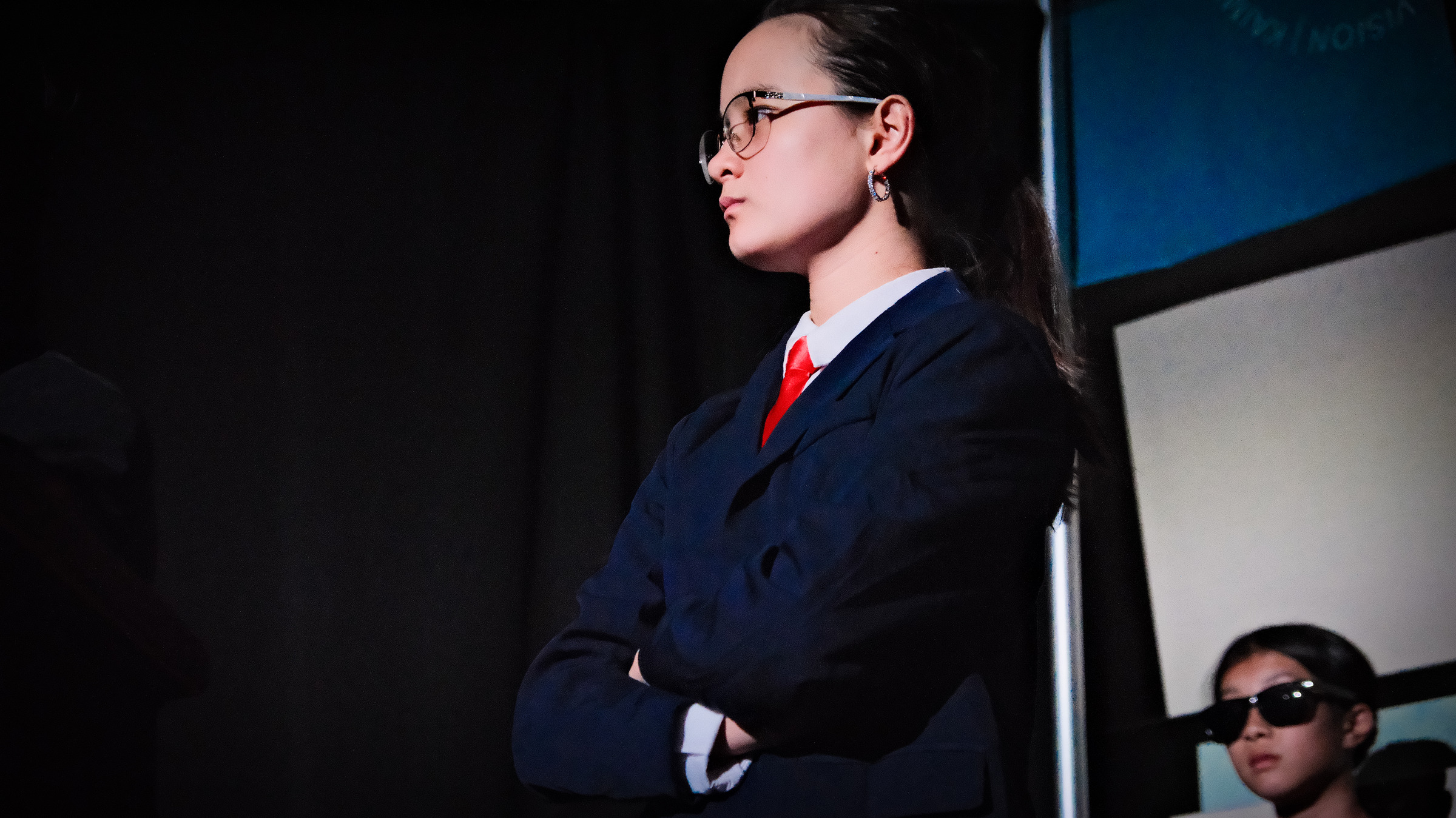 Character in navy suit, arms crossed